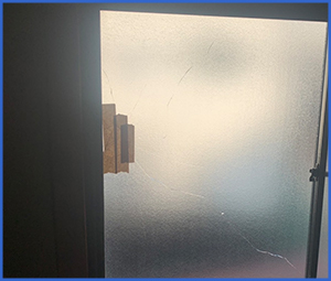 夜に割れたガラスを窓に貼ったガムテで補強しているのを外から写した画像