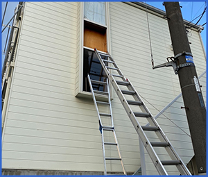 窓に梯子がかかった白い家を外からみた画像